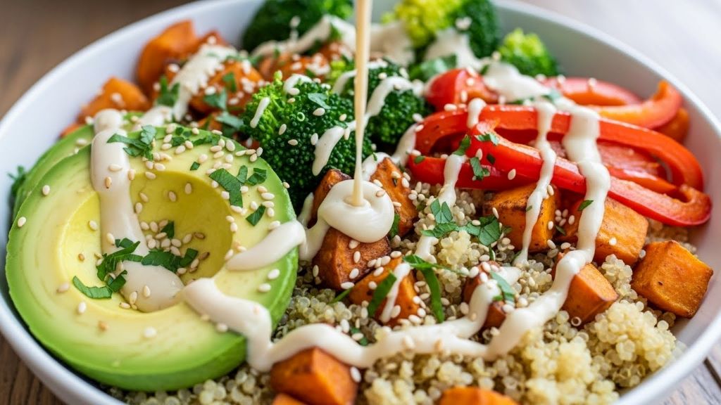 Colorful whole food meal bowl with quinoa, roasted vegetables, avocado, and tahini dressing for digestive health