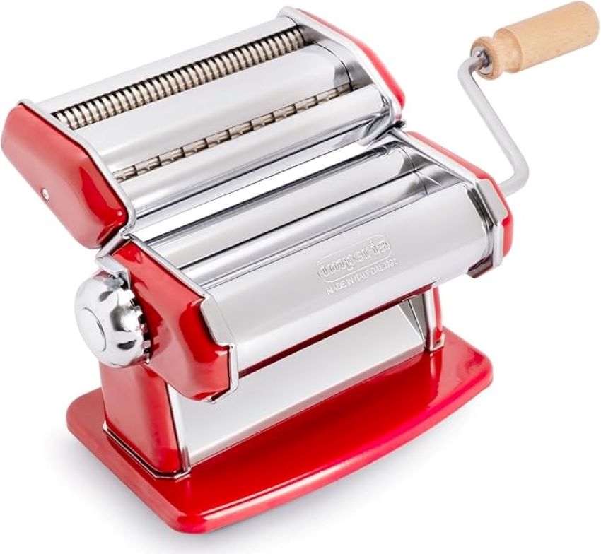 Fresh pasta dough being rolled through an Imperia pasta maker during hands-on testing for a detailed review.